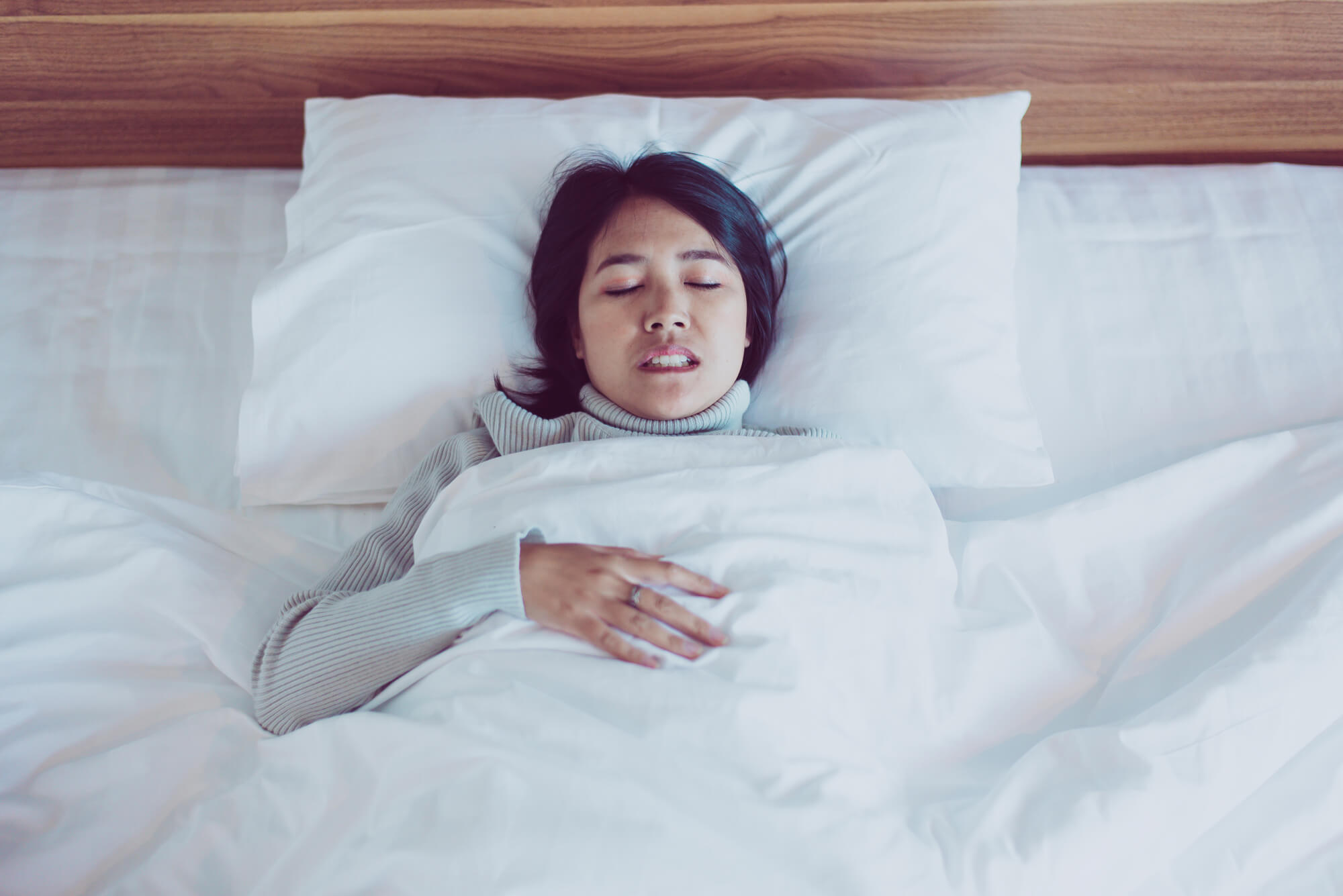 woman waking up with pain after grinding teeth during sleep